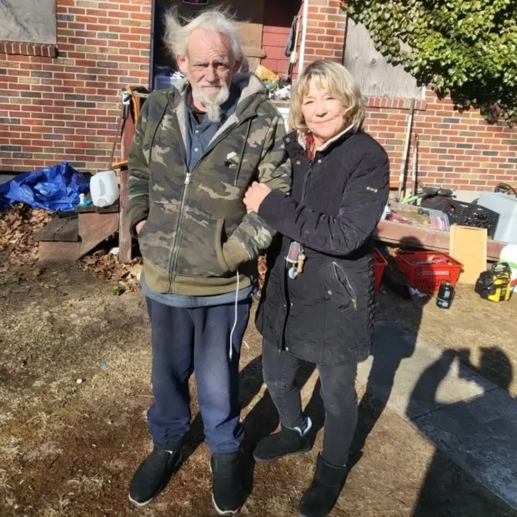 Wendy and Dennis posing for a photo in front of their home